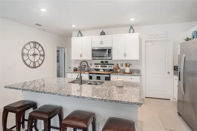 a kitchen with granite countertop a refrigerator a stove a sink a dining table and chairs