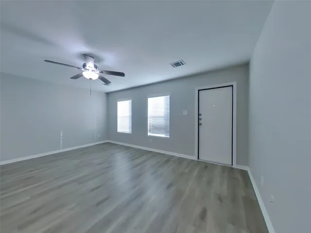 a view of an empty room with wooden floor and a window