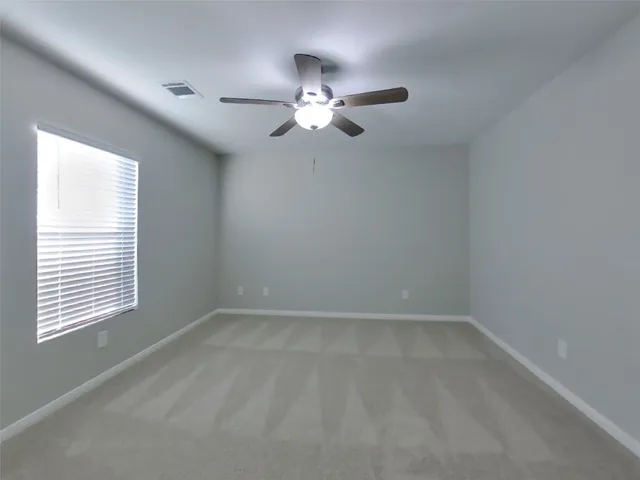 an empty room with a window and a fan