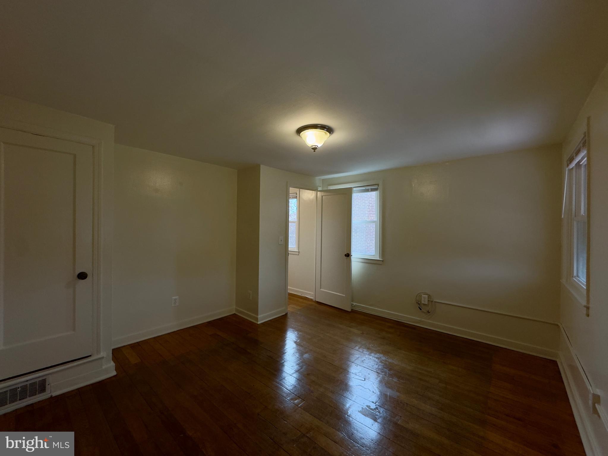 116 Carver Road Dundalk, MD 21222 - Photo 16 of 19 an empty room with wooden floor and windows with curtains