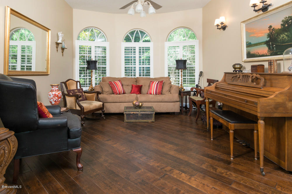 4175 Turtle Mound Road Melbourne, FL 32934 - Photo 2 of 26 a living room with furniture two large windows and wooden floor