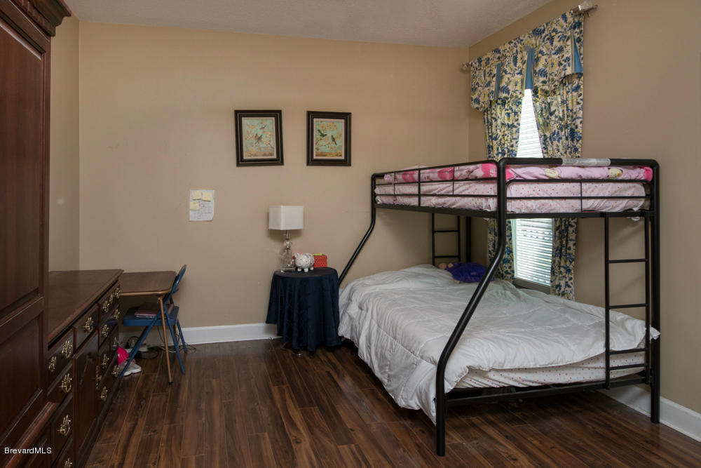 4175 Turtle Mound Road Melbourne, FL 32934 - Photo 12 of 26 a bedroom with a bed and wooden floor