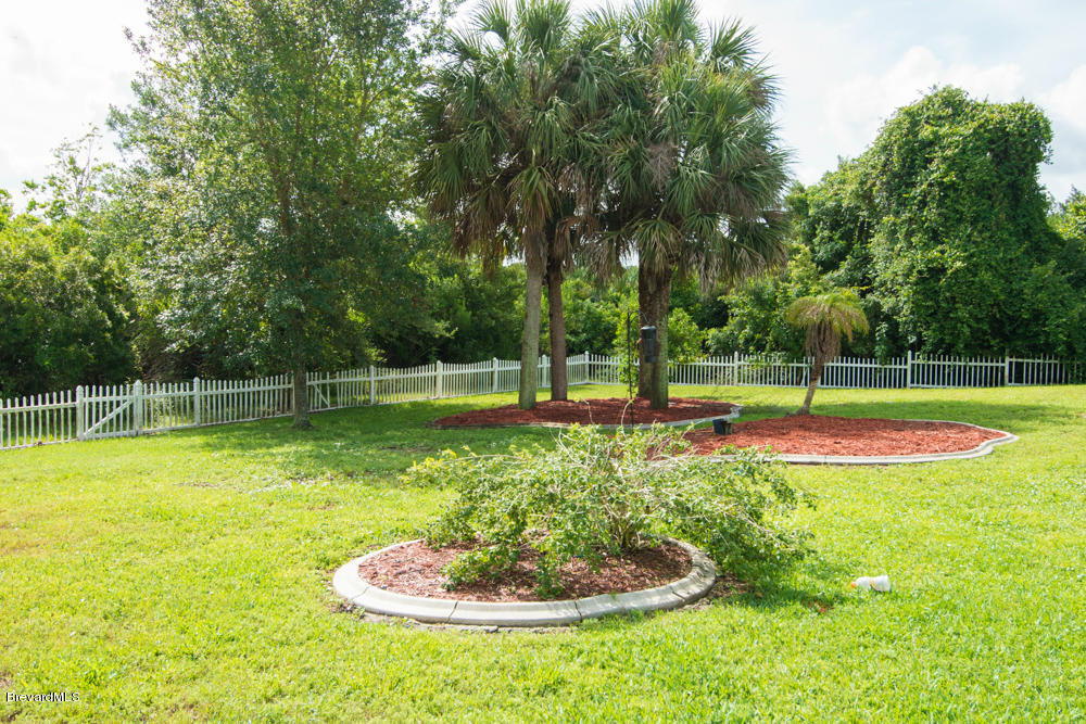 4175 Turtle Mound Road Melbourne, FL 32934 - Photo 24 of 26 a swimming pool with lots of green space and trees in the background