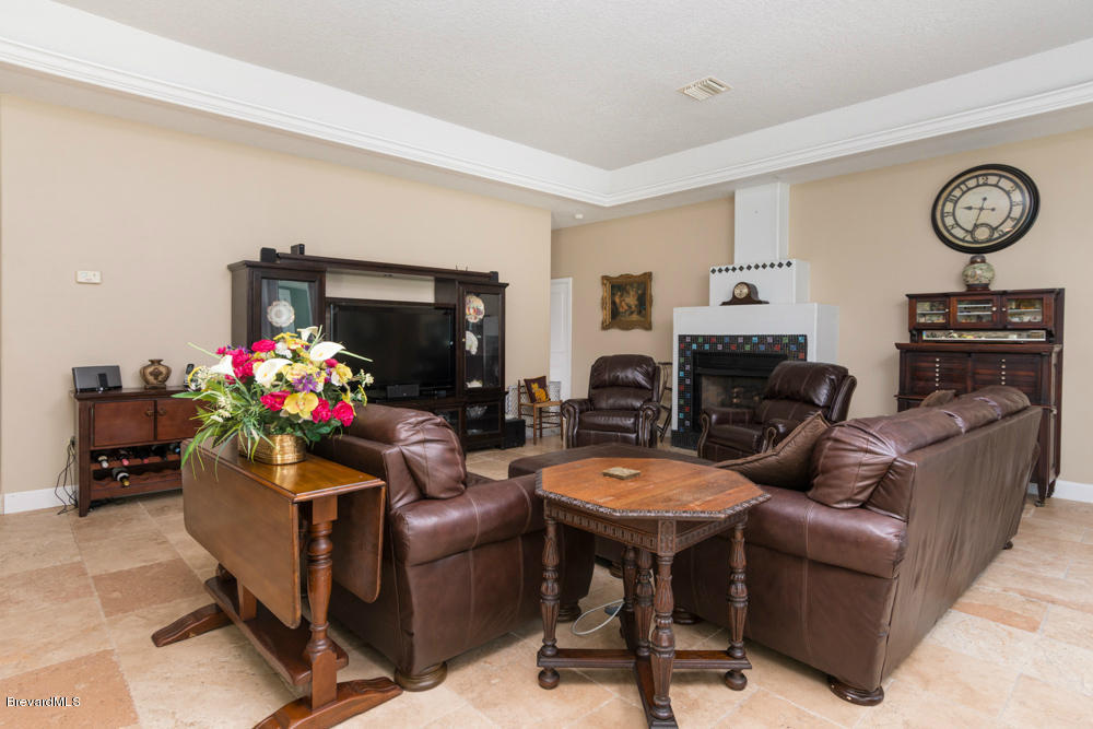 4175 Turtle Mound Road Melbourne, FL 32934 - Photo 5 of 26 a living room with furniture a fireplace and a flat screen tv