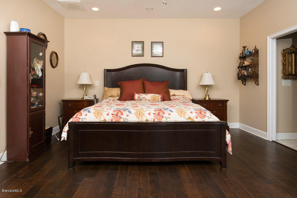 4175 Turtle Mound Road Melbourne, FL 32934 - Photo 8 of 26 a bed sitting in a bedroom next to a window with wooden floor