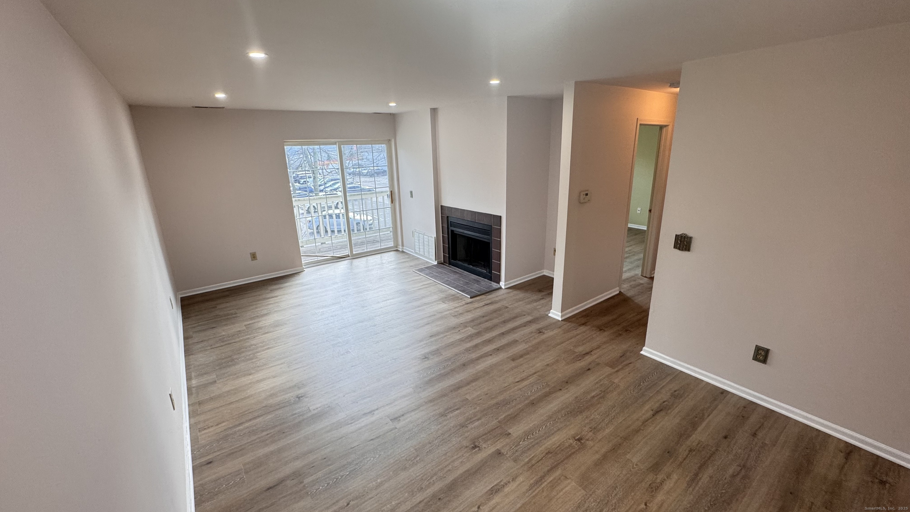 25 Janet Circle, Unit F Bridgeport, CT 06606 - Photo 3 of 22 an empty room with wooden floor and fireplace