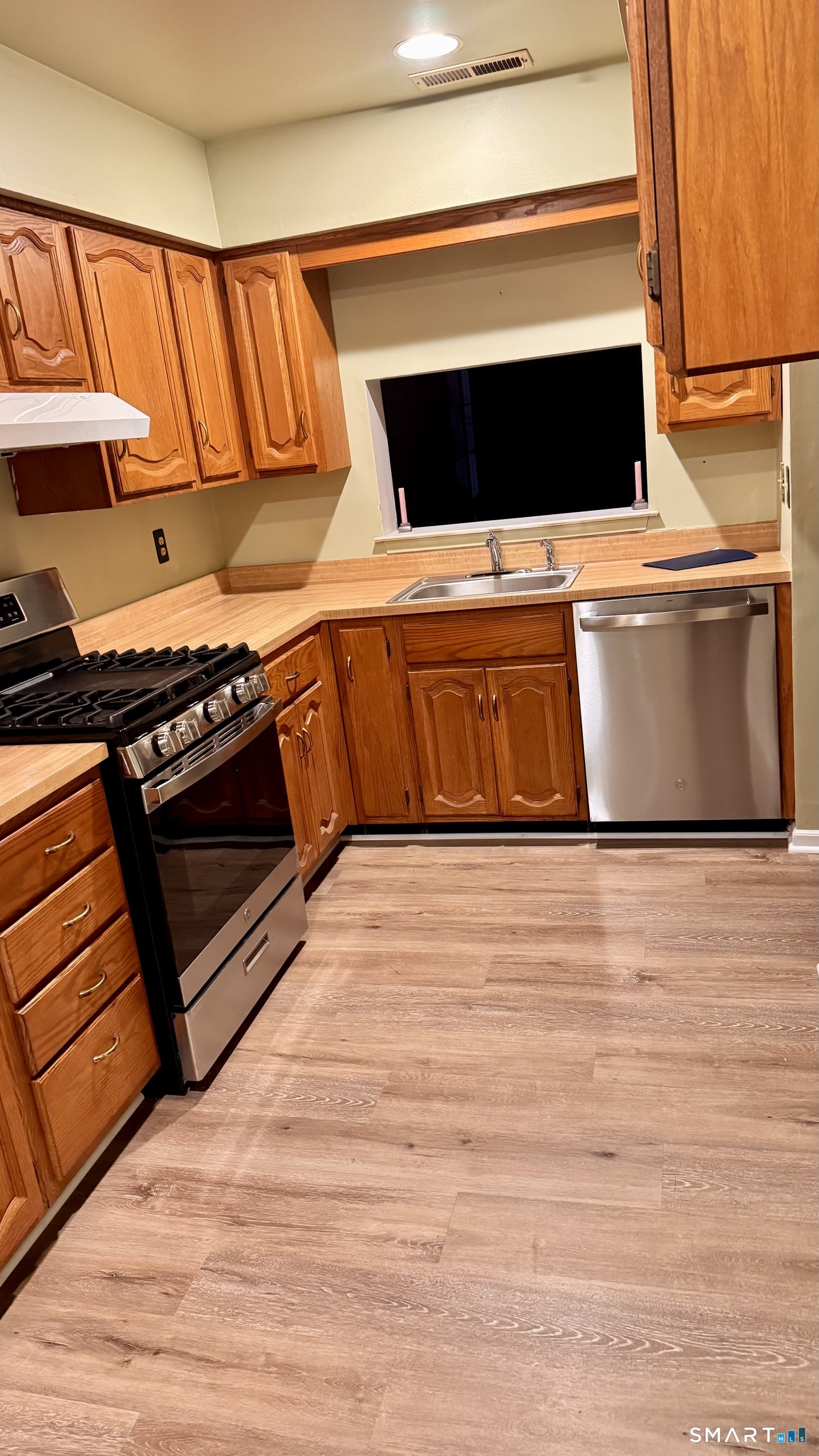 25 Janet Circle, Unit F Bridgeport, CT 06606 - Photo 9 of 23 a kitchen with stainless steel appliances wooden cabinets and a stove top oven