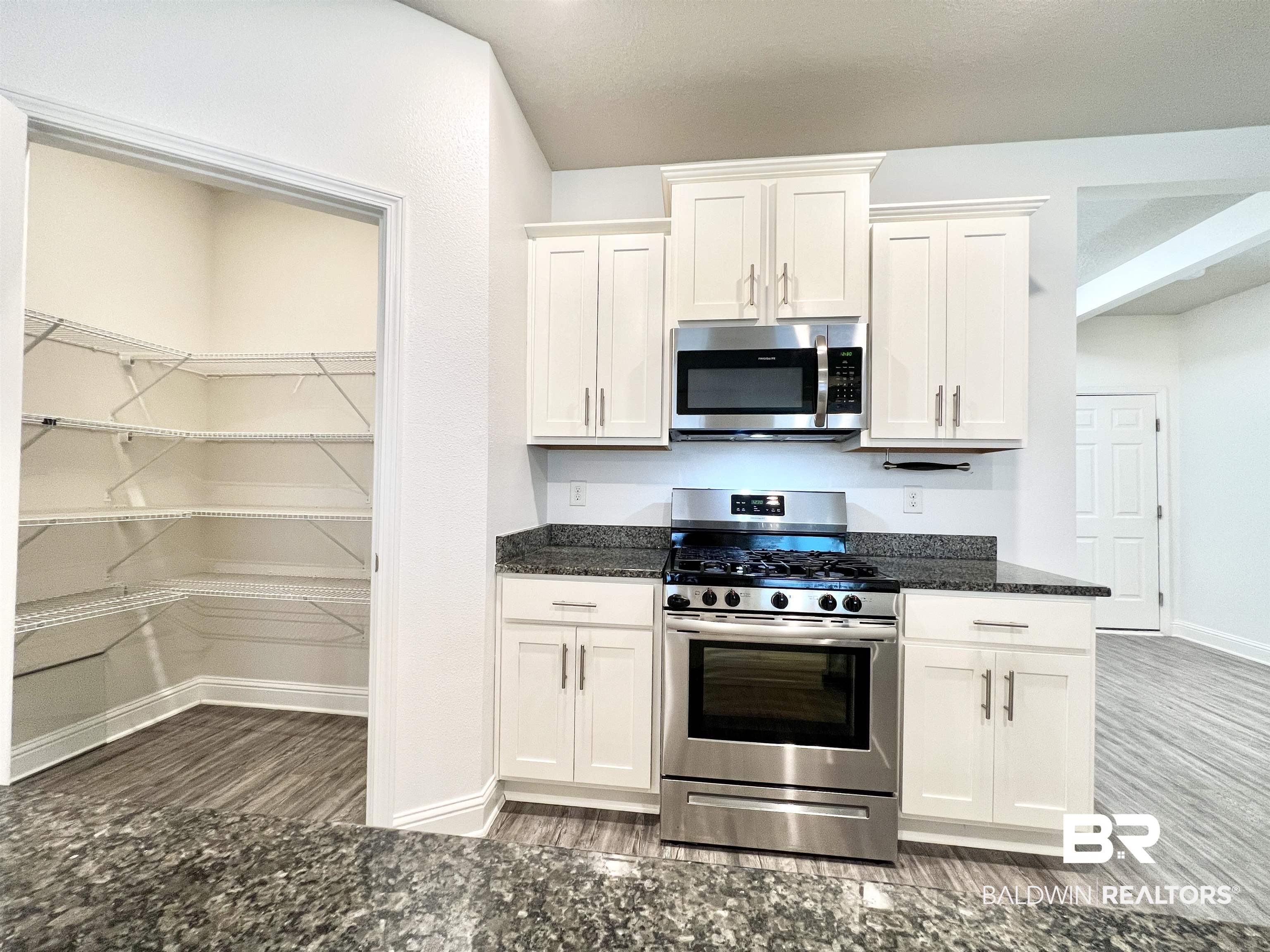 24785 Slater Mill Road Daphne, AL 36526 - Photo 7 of 46 Kitchen with dark stone countertops, appliances with stainless steel finishes, hardwood / wood-style floors, and white cabinets