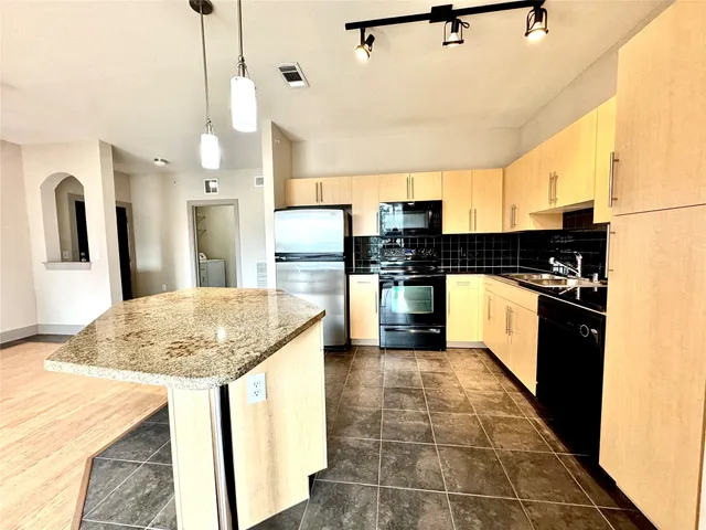 a kitchen with kitchen island granite countertop a sink a counter top space appliances and cabinets