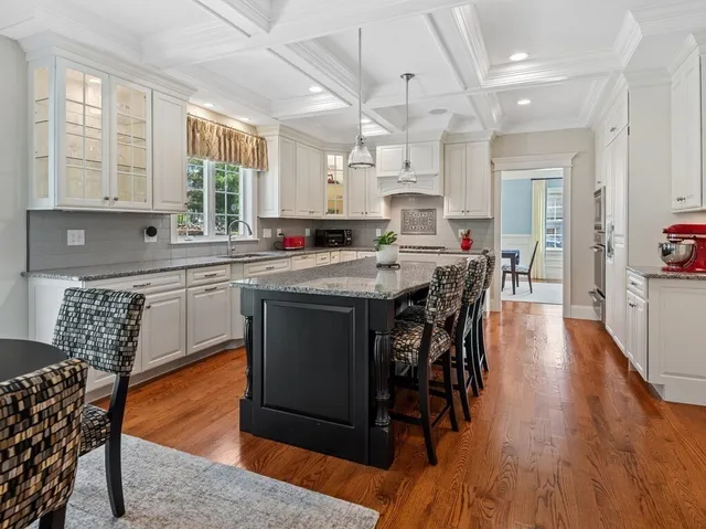 a kitchen with stainless steel appliances granite countertop a table chairs sink and cabinets