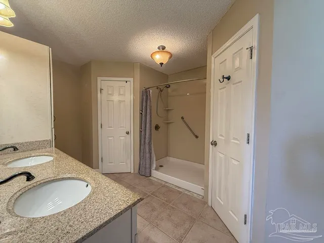 a bathroom with a granite countertop sink a mirror a bathtub and shower