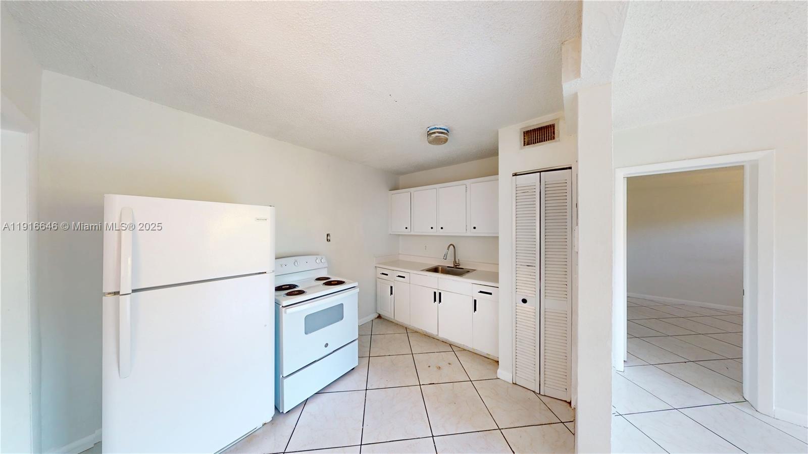 1825 Southwest 67th Avenue, Unit 24 West Miami, FL 33155 - Photo 2 of 11 a kitchen with white cabinets and white appliances
