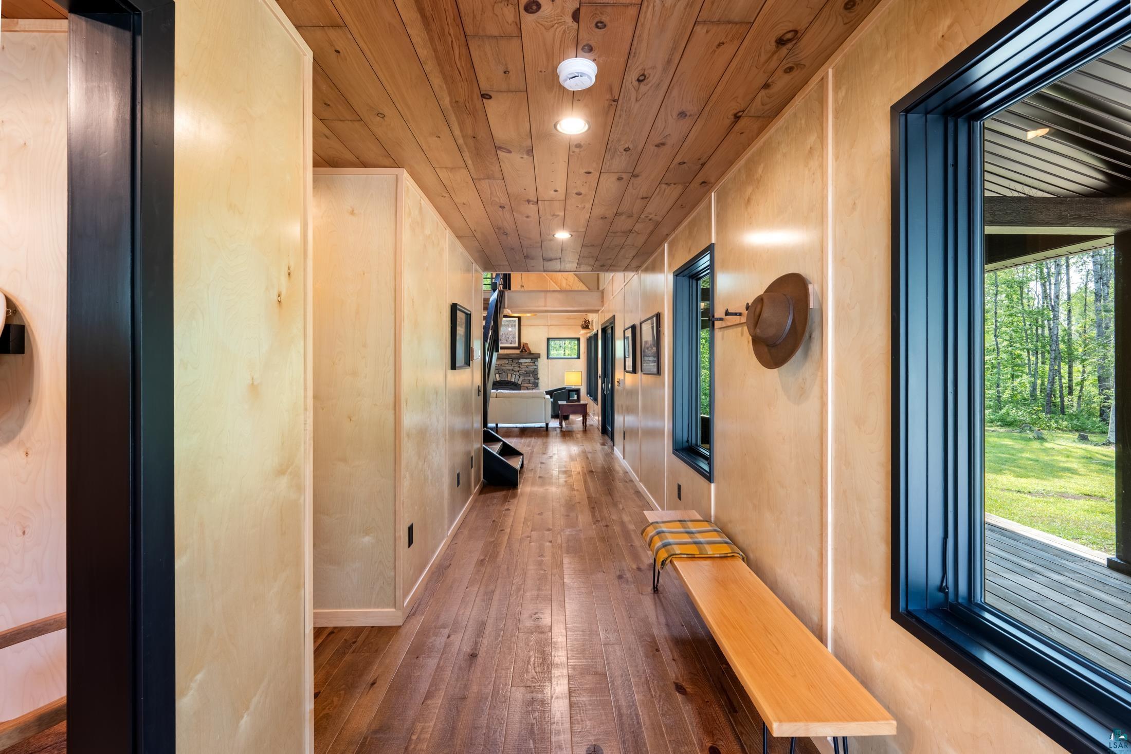 3778 East County Road Barnum, MN 55707 - Photo 12 of 52 Bright hallway with wood-finish flooring, wooden ceiling with recessed lighting, and large black-framed windows and glass doors opening to natural landscape