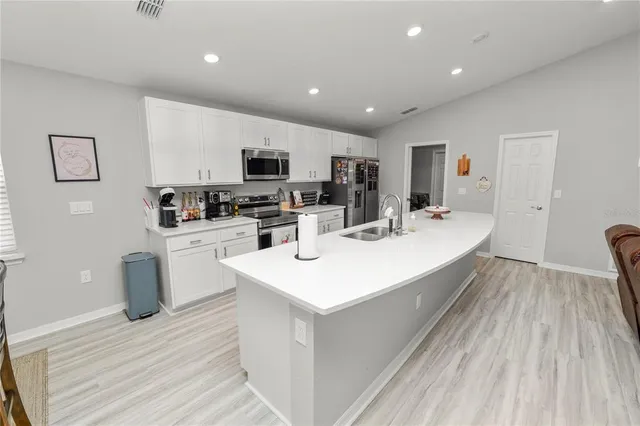 a kitchen with a sink a counter top space stainless steel appliances and cabinets
