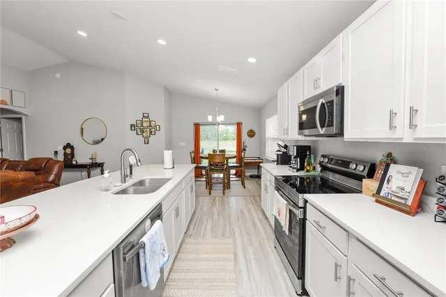 a large white kitchen with sink and chairs