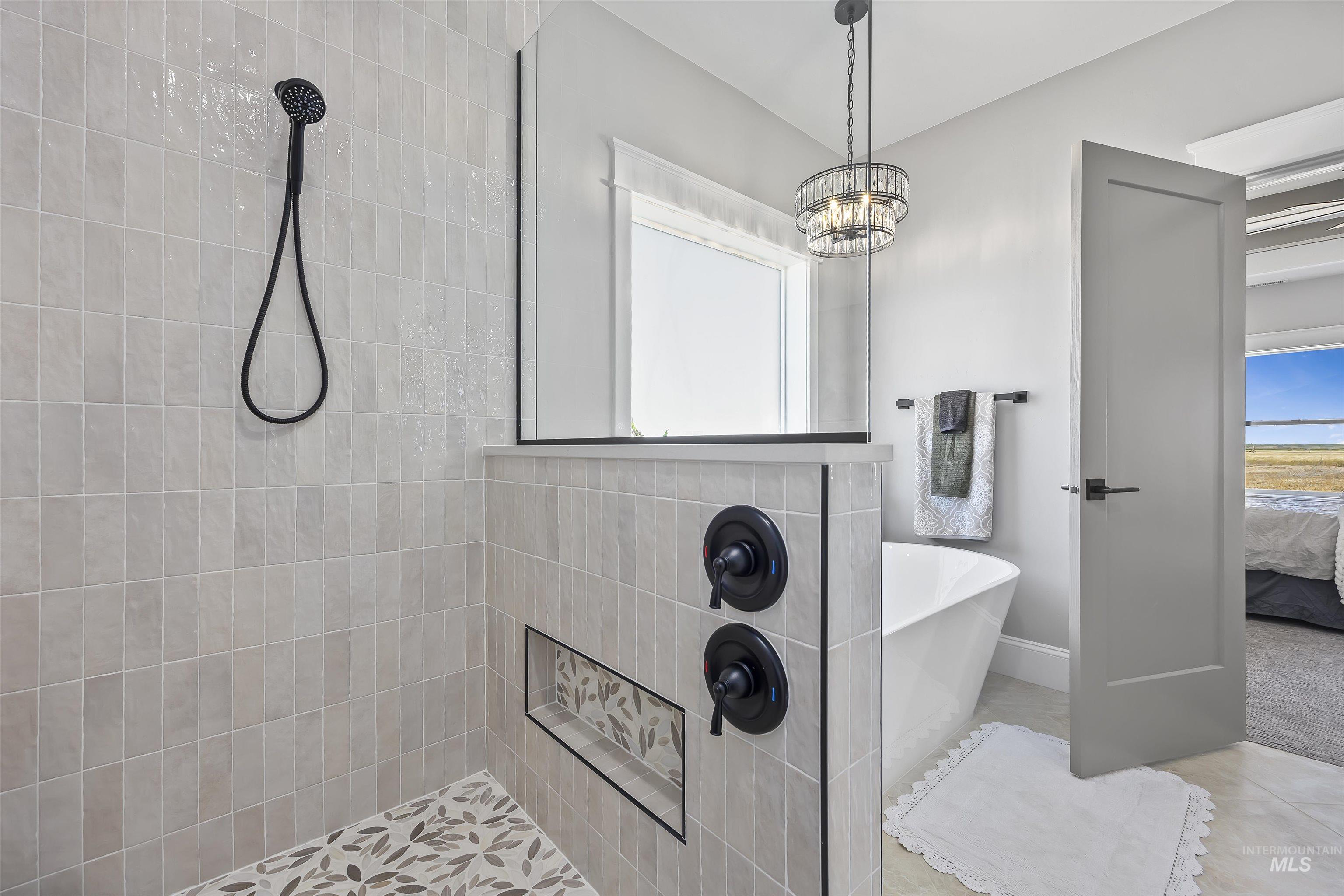 378 West 100 South Rupert, ID 83350 - Photo 29 of 50 Modern bathroom featuring a tiled shower with a black handheld showerhead, a built-in shower niche with decorative tile, and a freestanding soaking tub