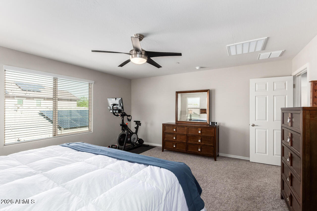 21188 West Almeria Road Buckeye, AZ 85396 - Photo 12 of 43 a bedroom with a bed and a chandelier