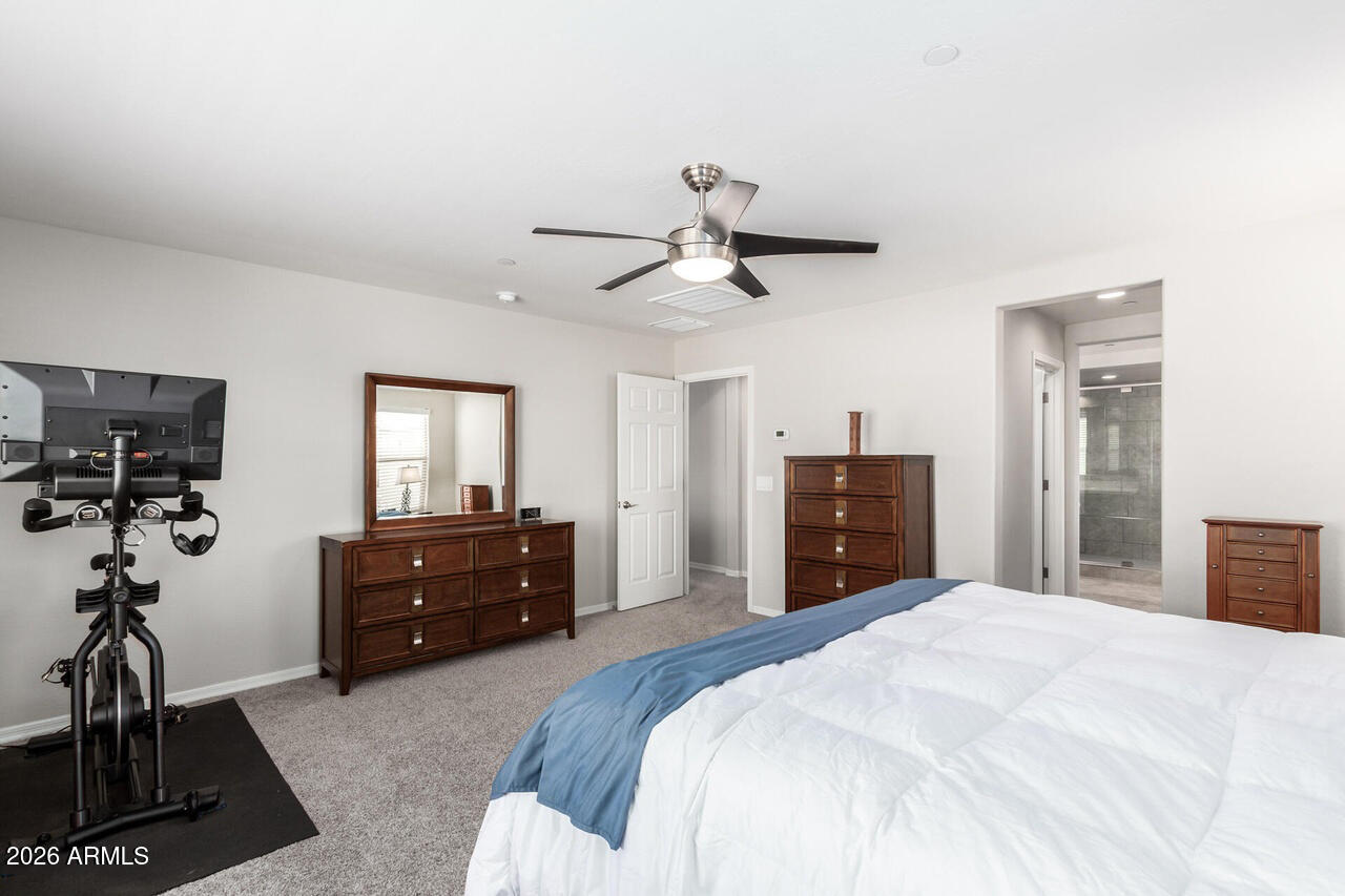 21188 West Almeria Road Buckeye, AZ 85396 - Photo 13 of 43 a bedroom with a bed and a chandelier