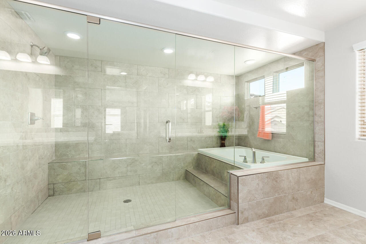 21188 West Almeria Road Buckeye, AZ 85396 - Photo 14 of 43 a bathroom with a bath tub a shower a sink and a mirror