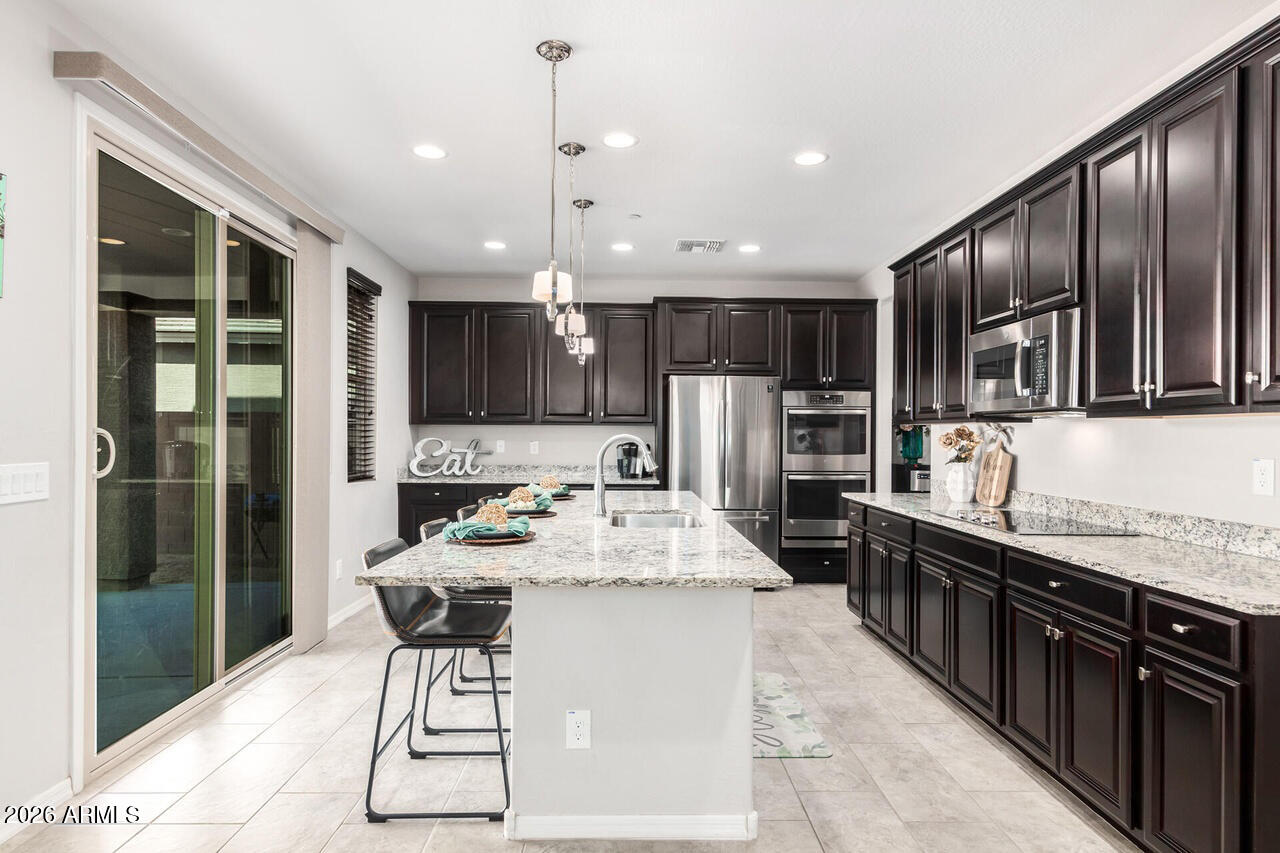 21188 West Almeria Road Buckeye, AZ 85396 - Photo 2 of 43 a kitchen with stainless steel appliances kitchen island granite countertop a sink refrigerator and cabinets