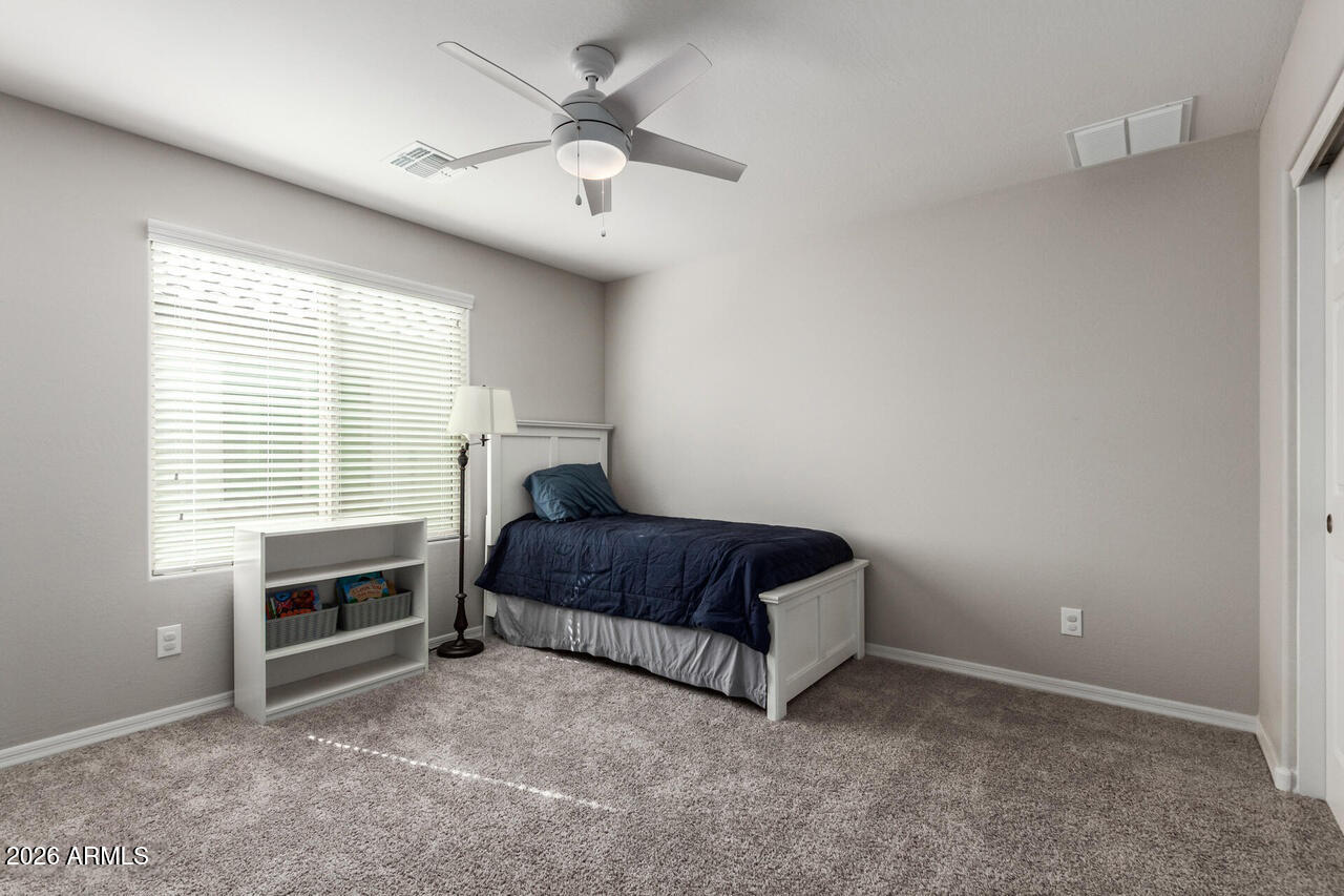 21188 West Almeria Road Buckeye, AZ 85396 - Photo 21 of 43 a living room with a bed furniture and a window