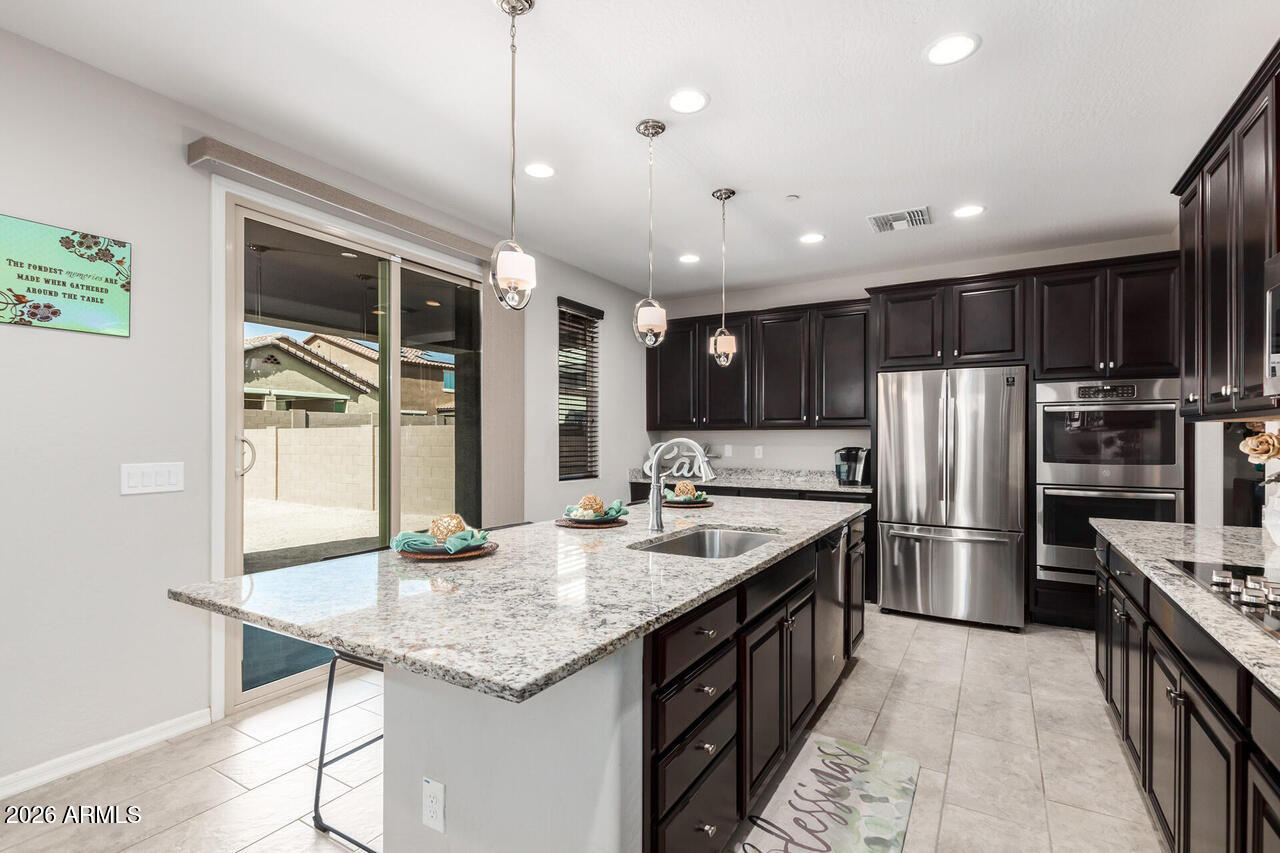 21188 West Almeria Road Buckeye, AZ 85396 - Photo 3 of 43 a kitchen with stainless steel appliances granite countertop a sink a stove and refrigerator