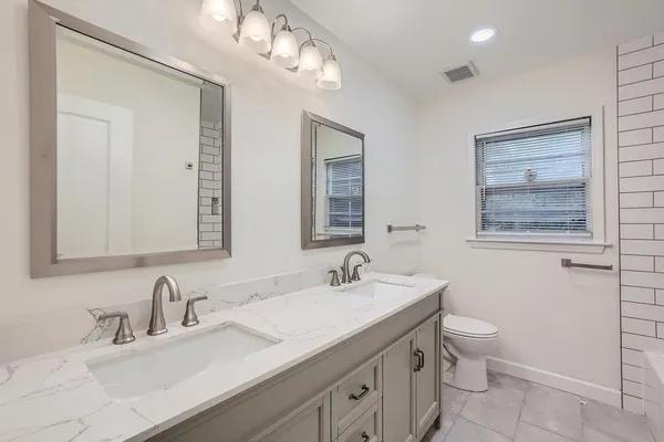 a bathroom with a toilet a sink a mirror and vanity