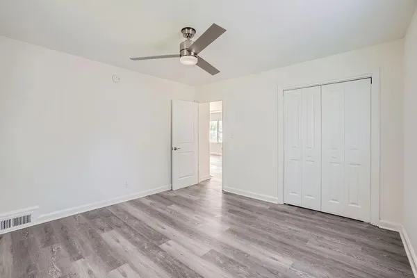 an empty room with wooden floor ceiling fan and windows