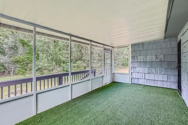 a view of an empty room with a window and hardwood