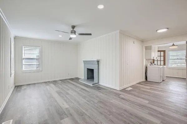 a view of a livingroom with a fireplace a ceiling fan and wooden floor