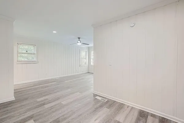 an empty room with wooden floor and windows