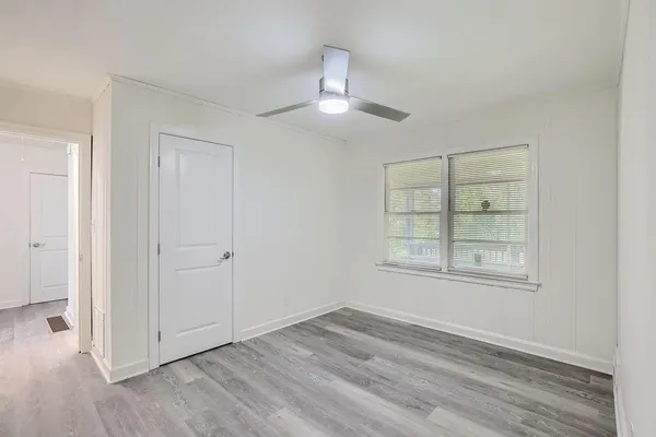 an empty room with wooden floor chandelier and windows