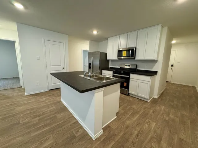 a kitchen with granite countertop a stove top oven and cabinets