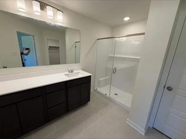 a spacious bathroom with a double vanity sink a mirror and a shower