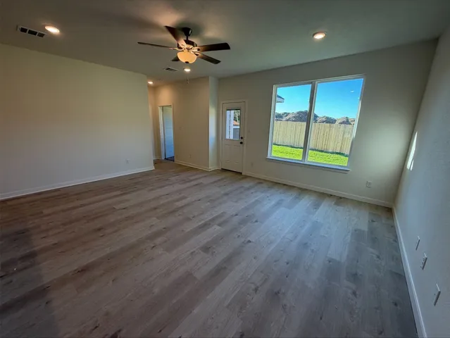a view of an empty room with a window and wooden floor