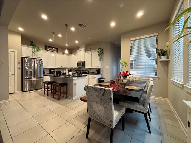a kitchen with a dining table chairs and refrigerator