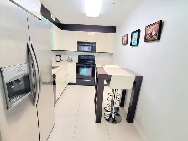 a view of a kitchen with fridge and workspace