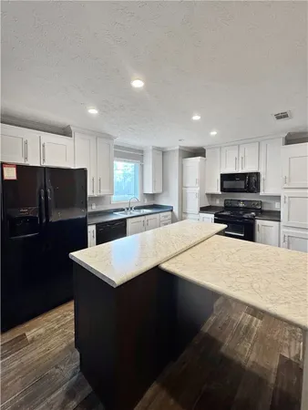 a kitchen with stainless steel appliances kitchen island sink refrigerator and cabinets