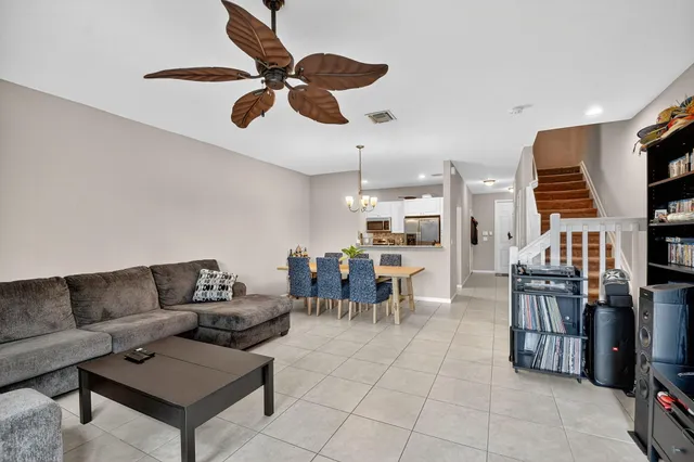 a living room with furniture kitchen view and a chandelier
