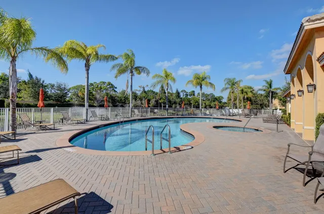 a view of a swimming pool with a lounge chair and palm trees