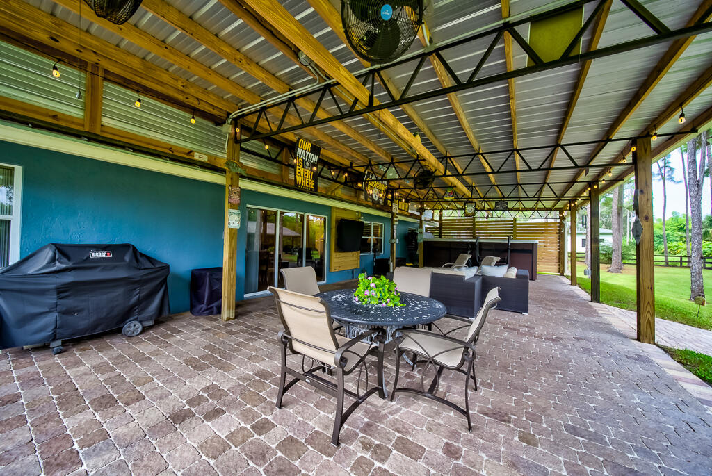 15733 Temple Boulevard Loxahatchee, FL 33470 - Photo 10 of 27 a view of a patio with table and chairs near a barbeque