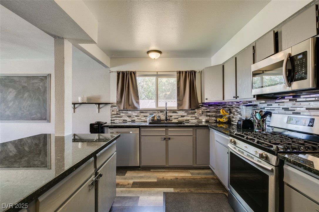 100 Huntly Road Las Vegas, NV 89145 - Photo 9 of 16 Kitchen with appliances with stainless steel finishes, a sink, gray cabinets, and backsplash
