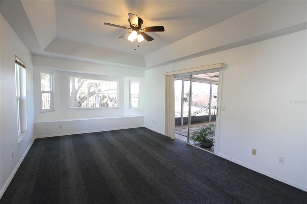 1414 Norwick Drive Lutz, FL 33559 - Photo 14 of 43 an empty room with wooden floor chandelier fan and windows