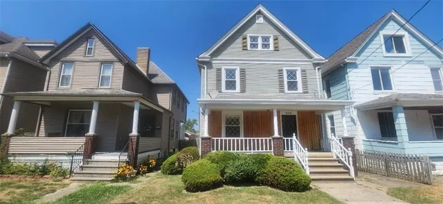 a view of a brick house with large windows and a yard