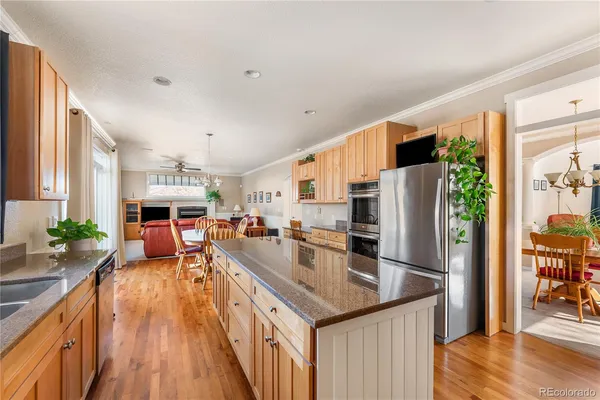 a kitchen with stainless steel appliances granite countertop a refrigerator a stove and a wooden floors