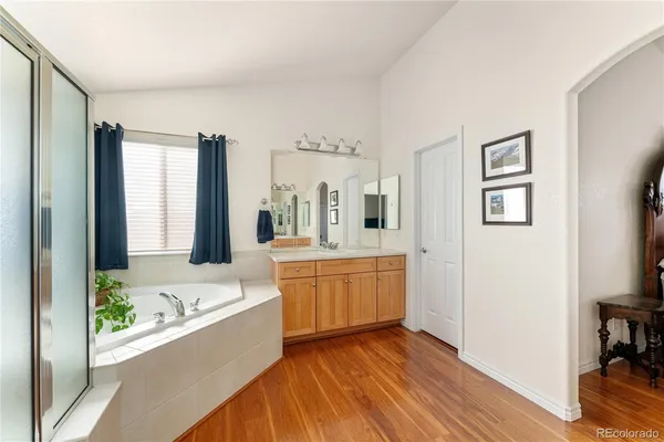 a large bathroom with a tub double vanity sink and mirror