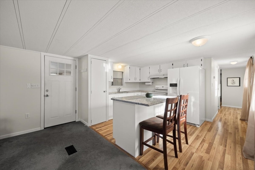 199 Windswept Road Wareham, MA 02571 - Photo 10 of 29 a kitchen with a table chairs refrigerator and wooden floor