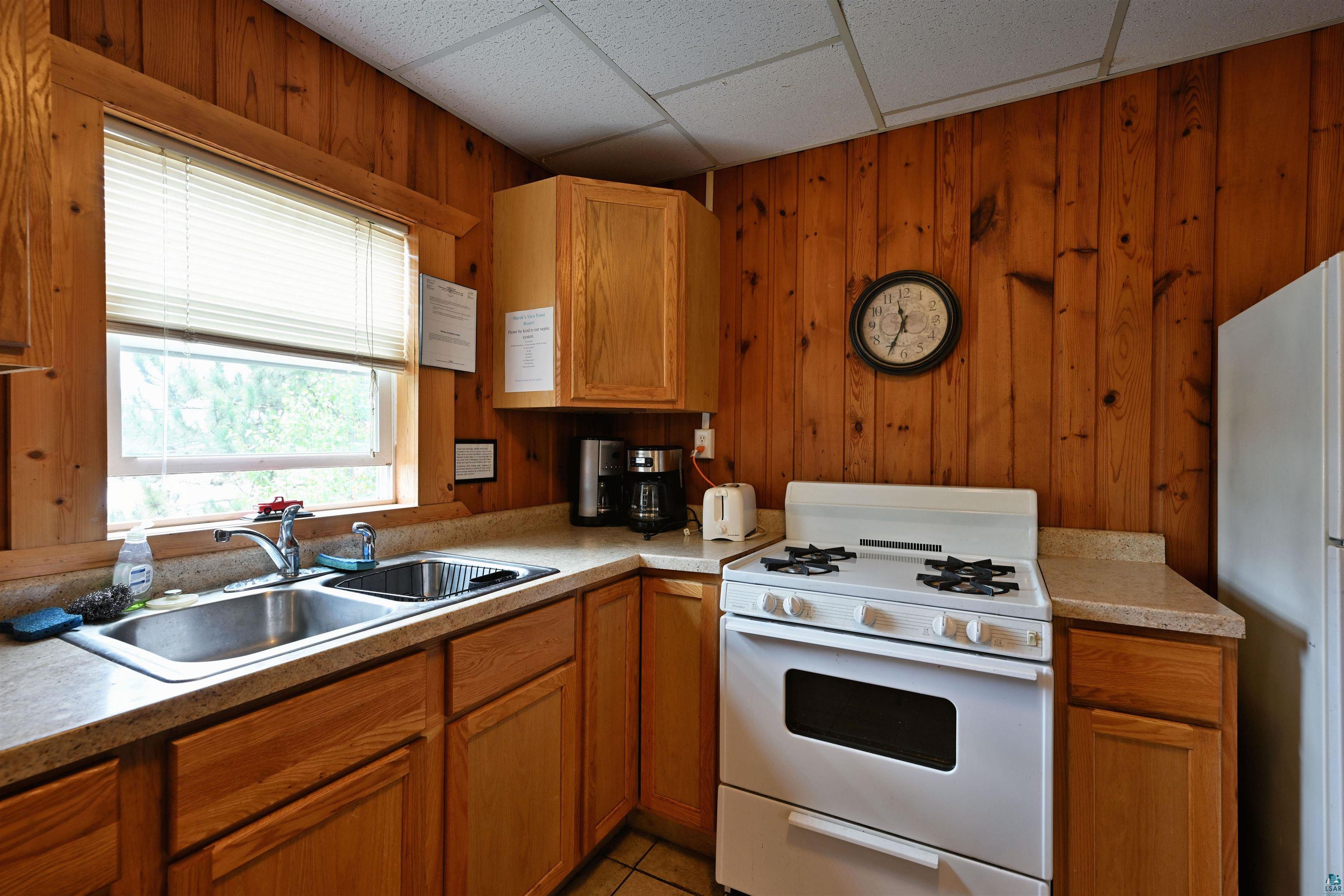 6833 View Point Lodge Road, Unit 14 Gordon, WI 54838 - Photo 13 of 34 Kitchen with white appliances, wood walls, wood finish cabinets, light countertops, and a drop ceiling