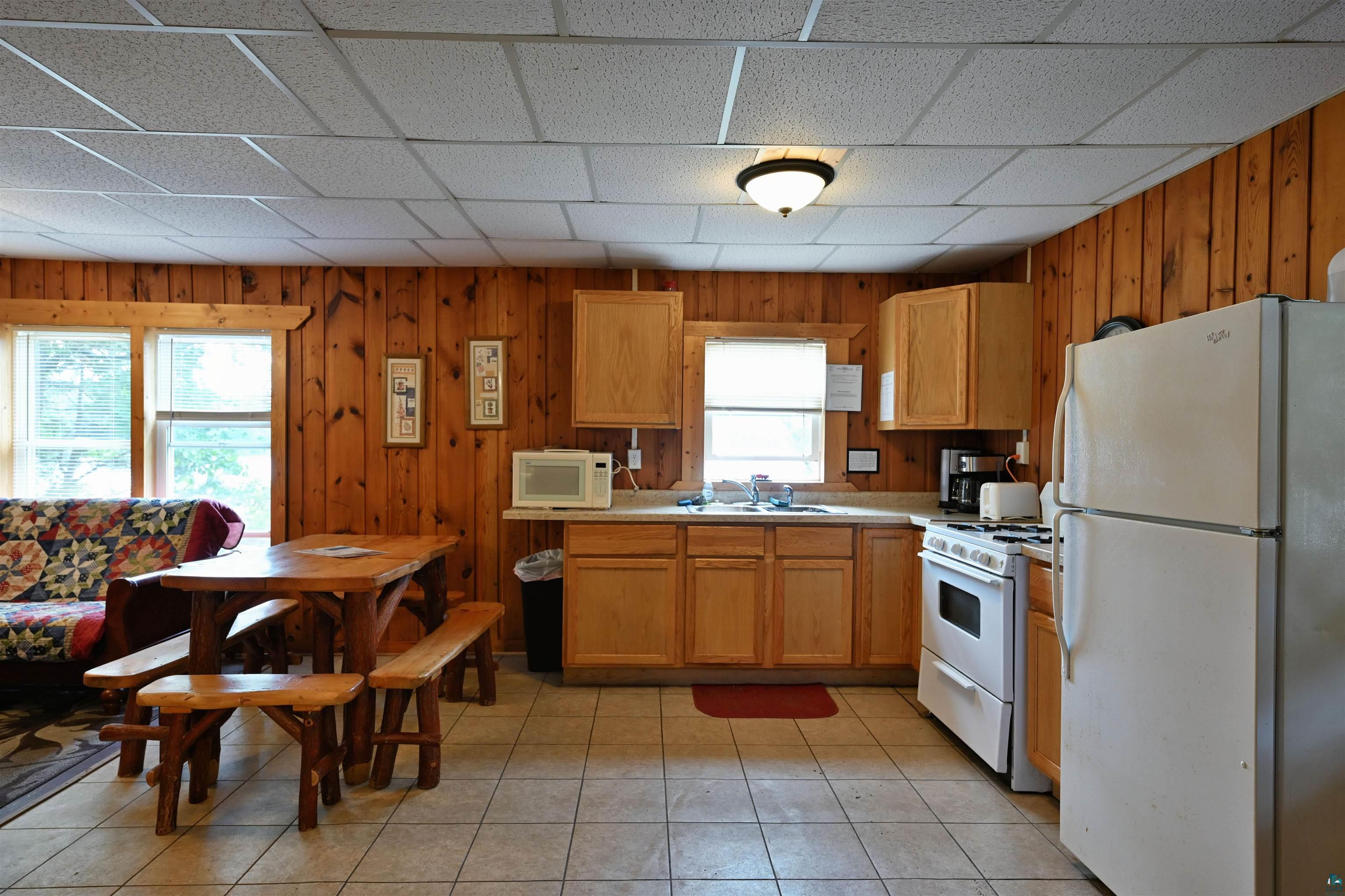 6833 View Point Lodge Road, Unit 14 Gordon, WI 54838 - Photo 16 of 34 Kitchen with white appliances, light countertops, wooden walls, a drop ceiling, and light tile patterned floors