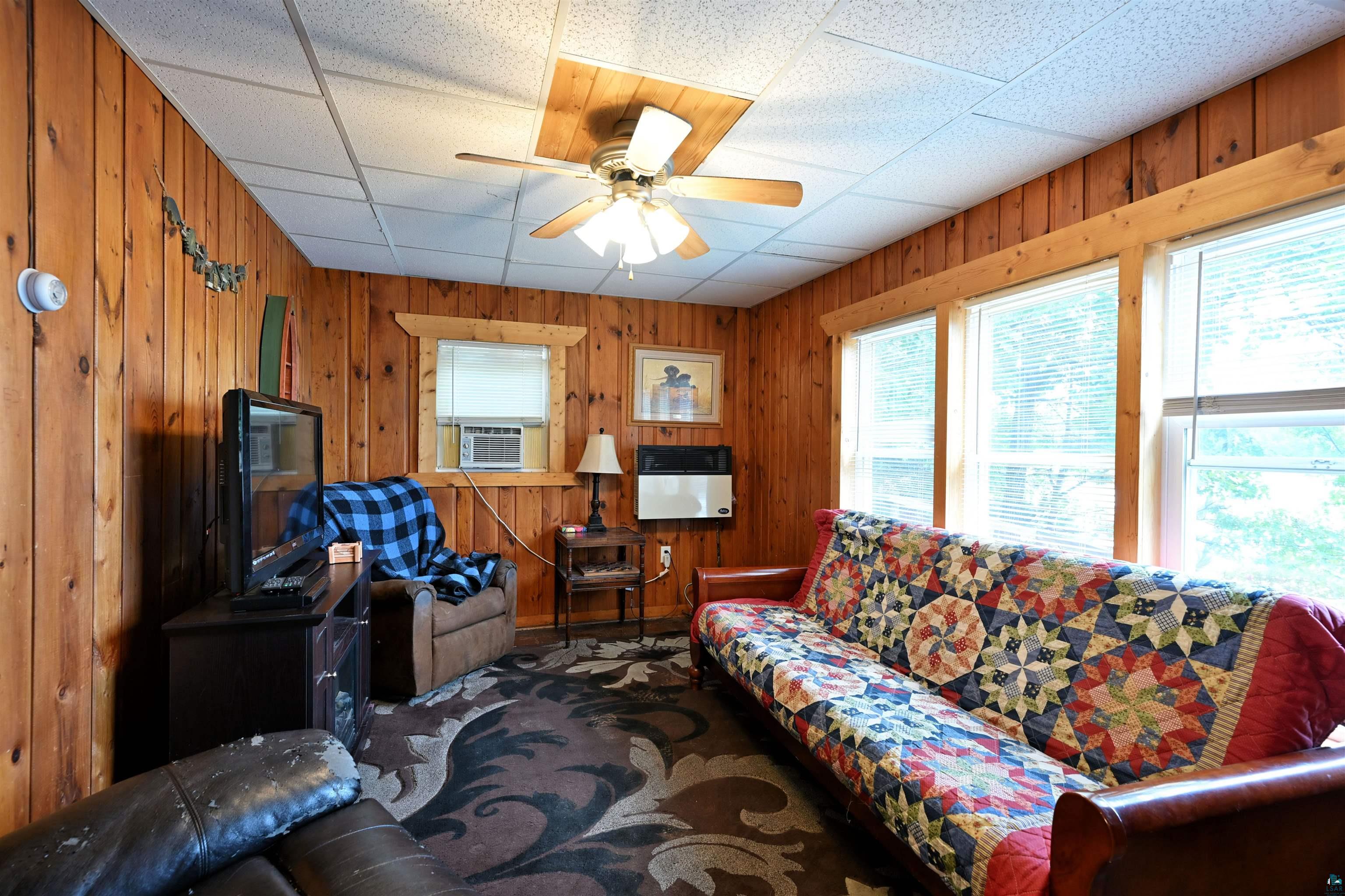 6833 View Point Lodge Road, Unit 14 Gordon, WI 54838 - Photo 20 of 34 Living area with ceiling fan, a drop ceiling, wooden walls, heating unit, and cooling unit